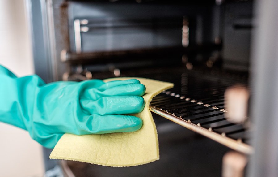 Man's hand cleaning the kitchen oven door